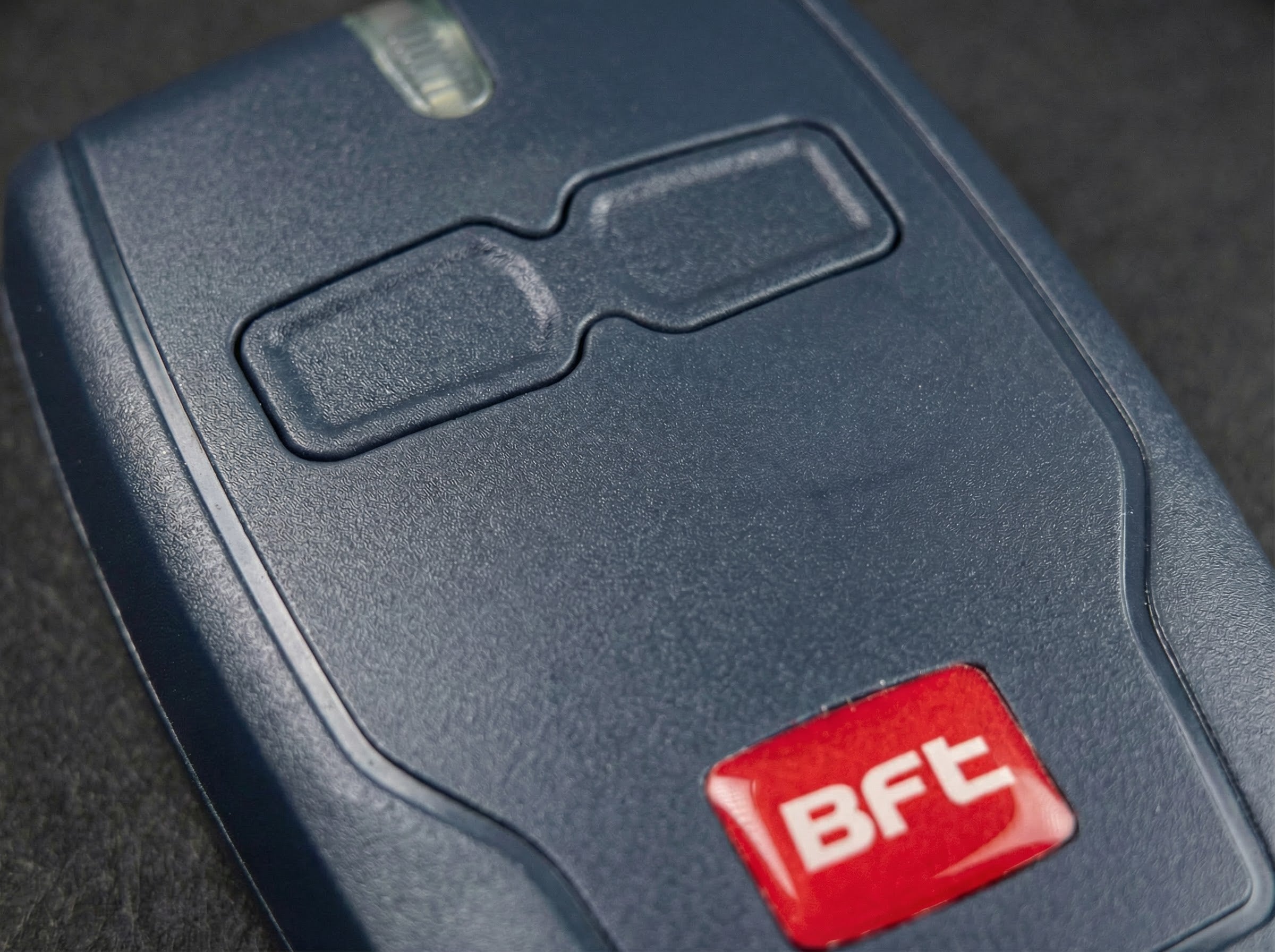 Close-up of a blue electronic device with a red 'BFT' logo on a dark background