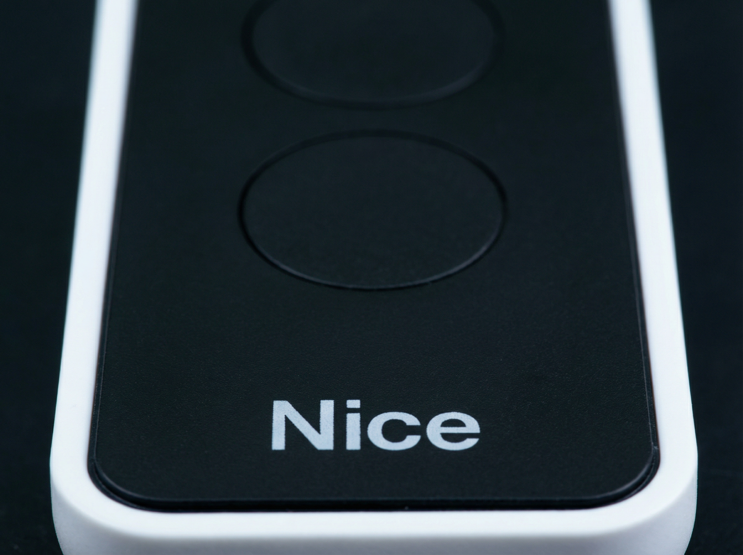 Close-up of a 'Nice' branded electronic device with two black buttons on a dark background