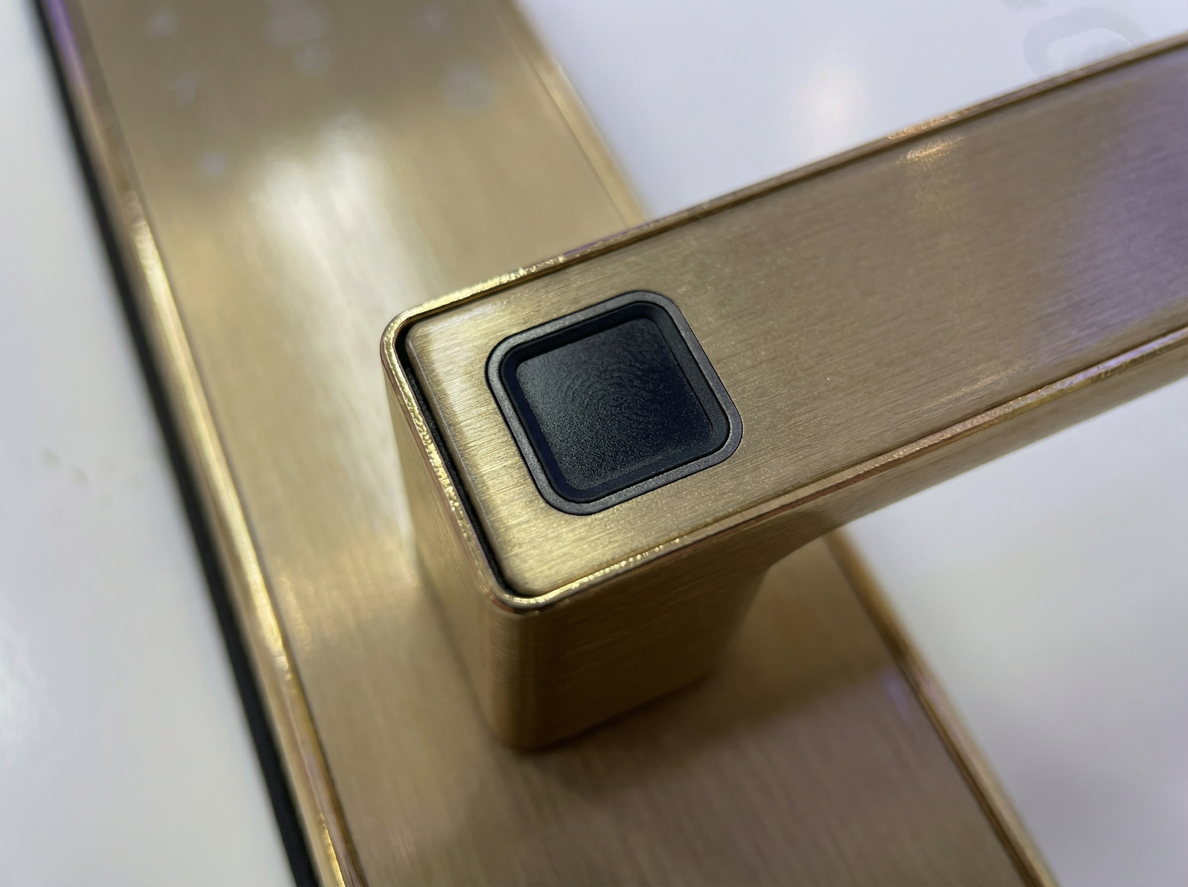 Gold door handle with a fingerprint sensor on a white background